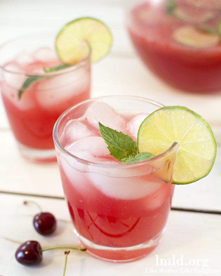 Front view of cherry limeade in glasses with a wood board underneath. 