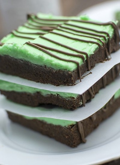 Angled view of chocolate mint sugar cookie bars stacked on a white plate.