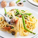 A plateful of asparagus carbonara, with a bite of it on a fork.
