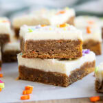 A stack of two carrot cake cookie bars with cream cheese frosting, and spring sprinkles on top.