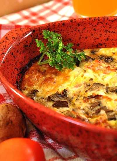 Angled view of baked omelet in a red casserole dish.