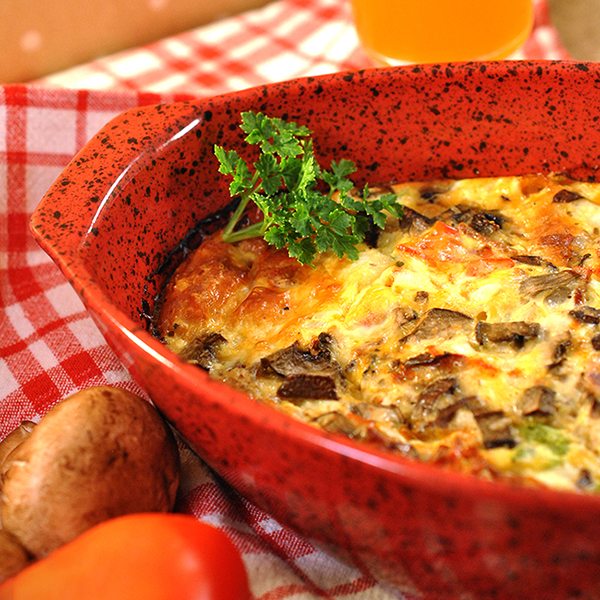 Angled view of baked omelet in a red casserole dish.