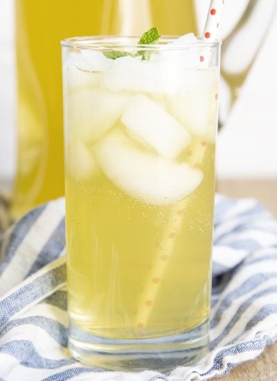 A glass of sparkling lemonade topped with ice and a mint leaf.