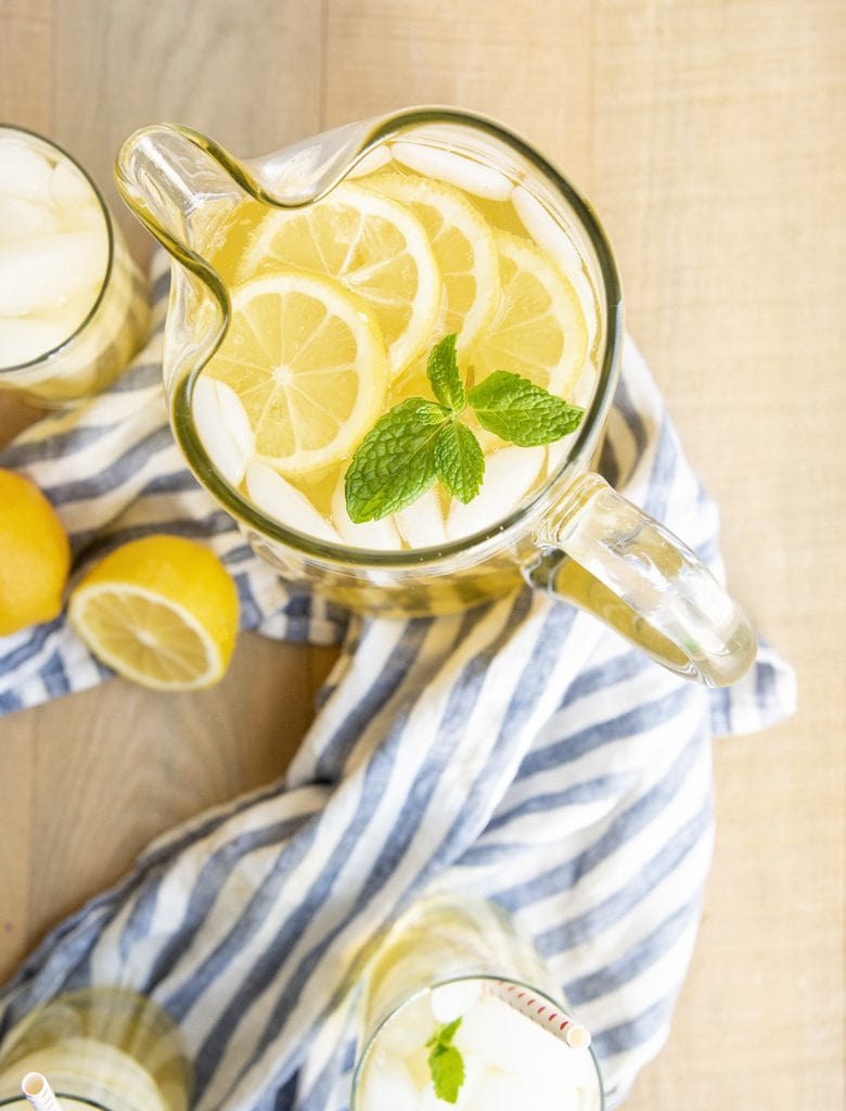 An overhead photo of a pitcher of lemonade topped with lemon slices and some fresh mint leaves.