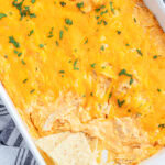 An above view of a pan of buffalo chicken dip with tortilla chips in it.