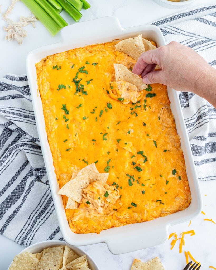 An above view of a pan of buffalo chicken dip with tortilla chips in it.