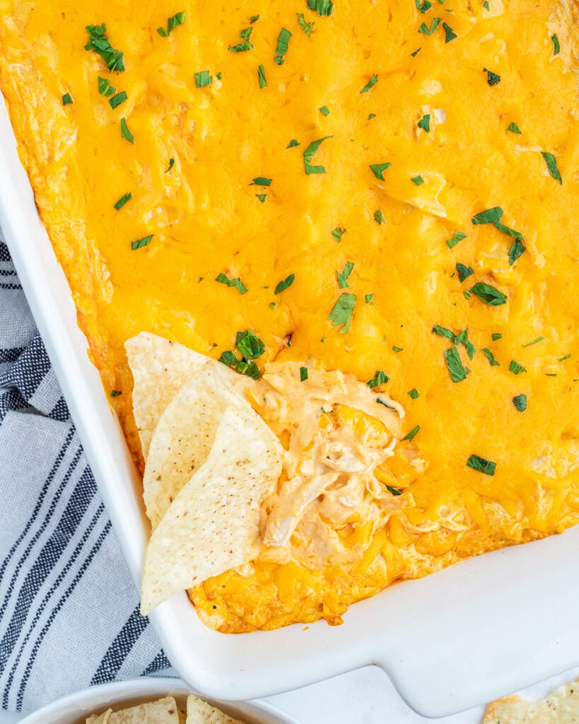 An above view of a pan of buffalo chicken dip with tortilla chips in it.