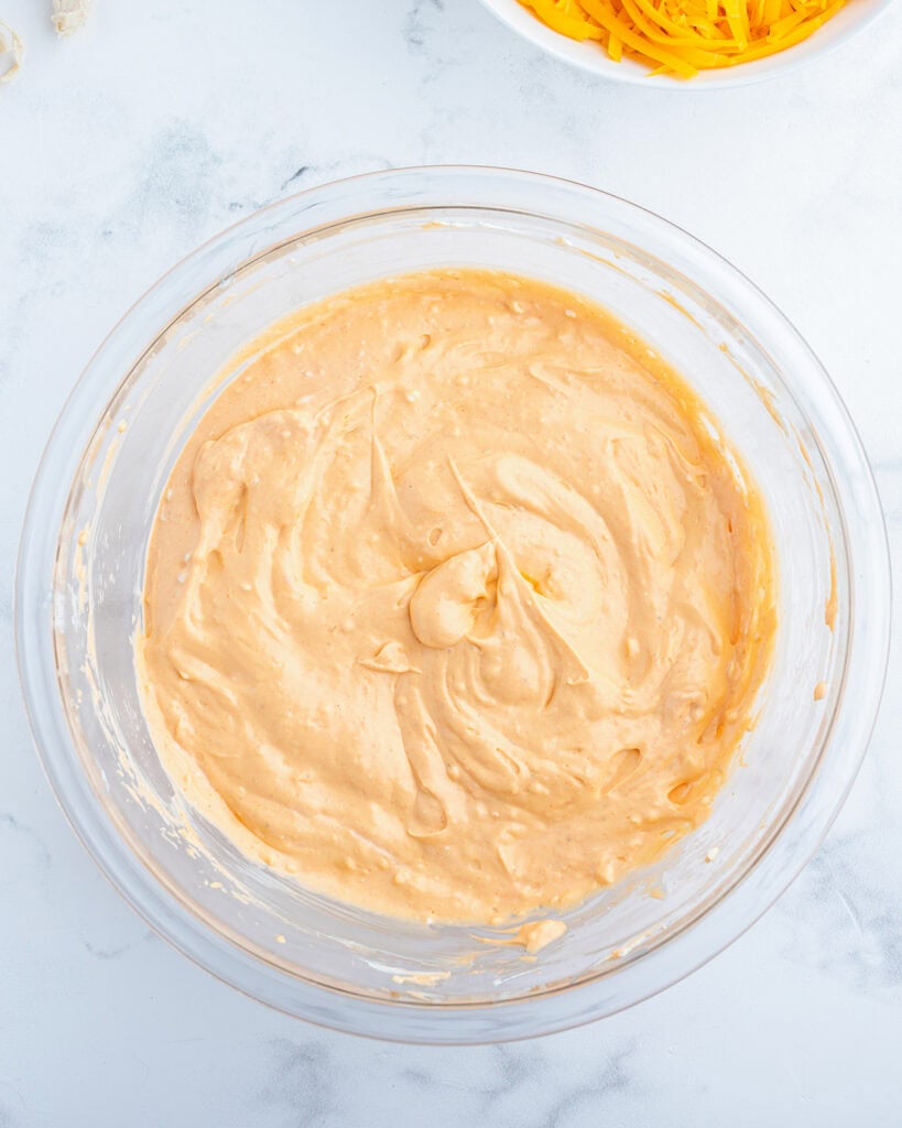 A bowl of a creamy orange mixture, that is hot sauce, and cream cheese mixed together.