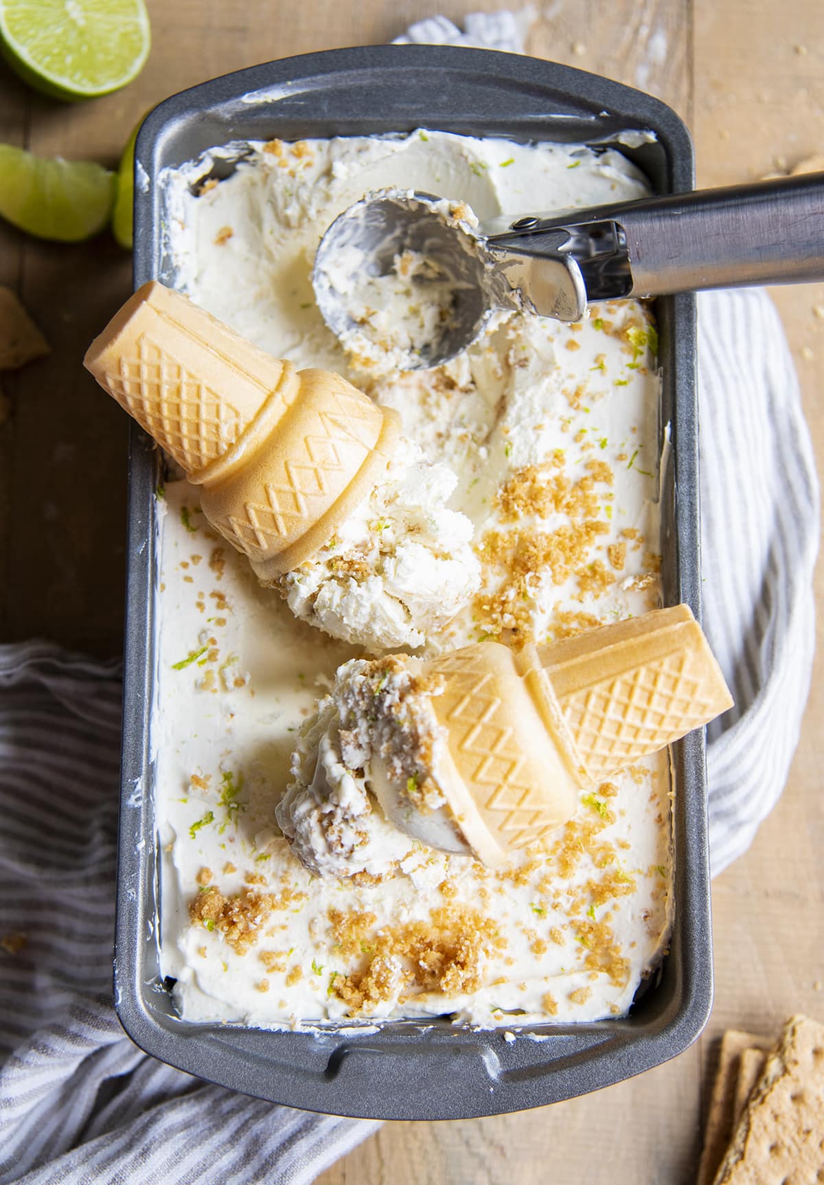 Two ice cream cones of key lime pie ice cream topped with a container of ice cream.