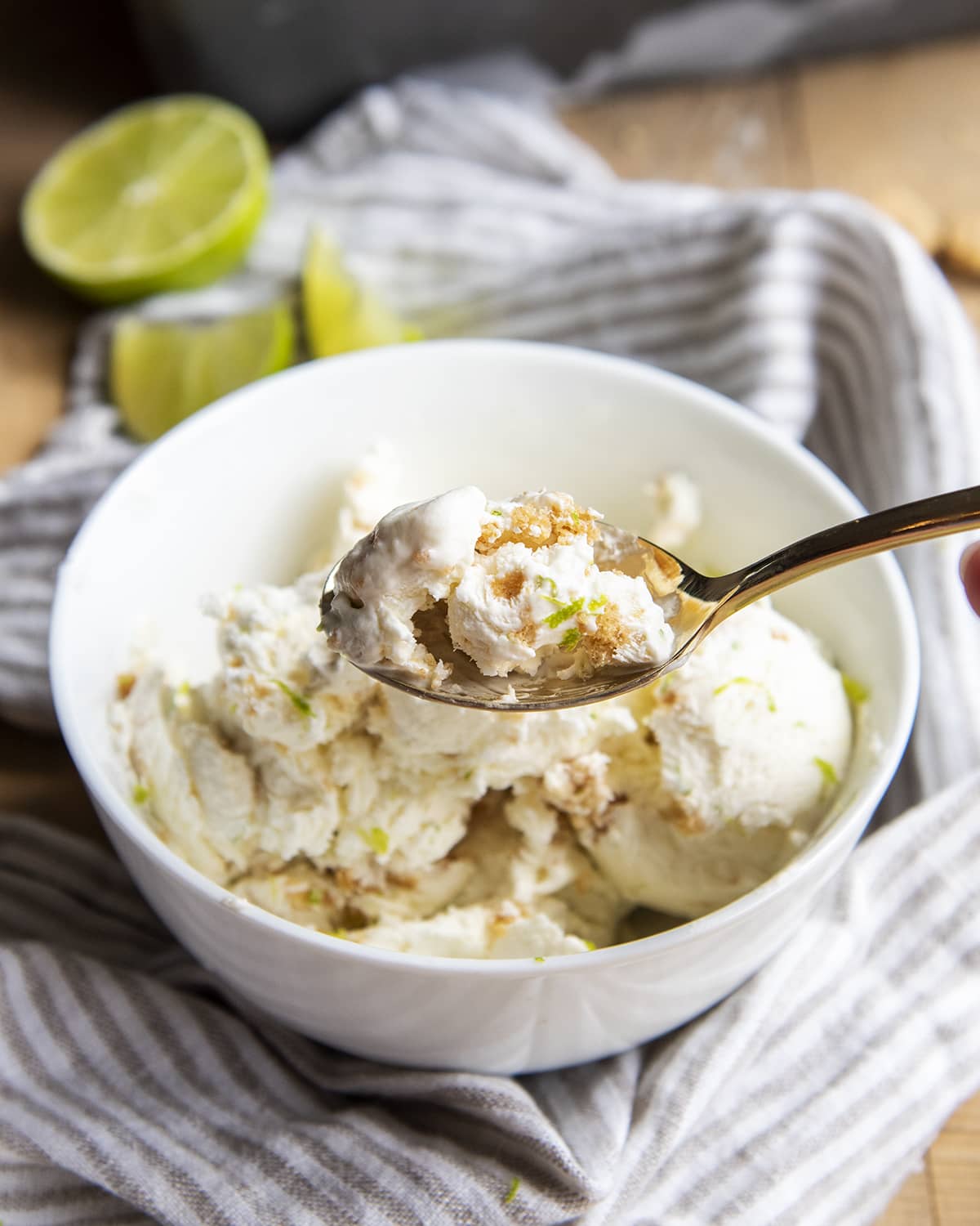 A spoonful of ice cream with graham cracker swirl above a bowl of key lime ice cream.