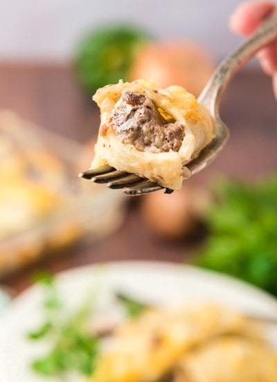 Close up image of philly cheese steak stuffed shells forkful with ingredients in background.