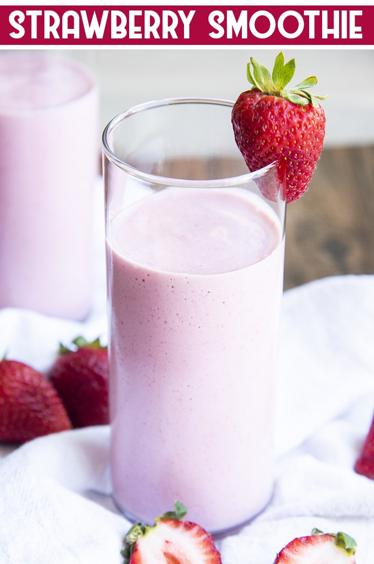 Close up image of strawberry yogurt smoothie in a glass with a strawberry on the glass rim.