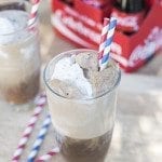 Angled view of a coke float in a glass cup with straw.