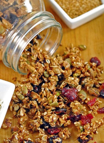 Angled view of nut and seed granola pouring out of a mason jar.