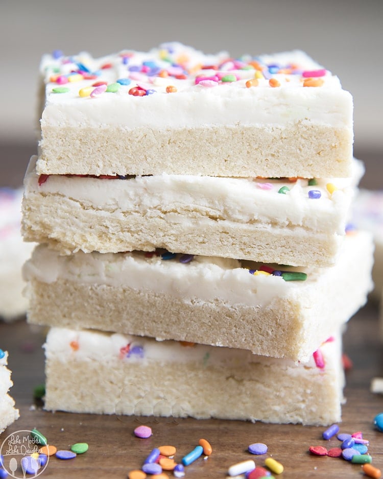 A stack of 4 sugar cookie bars, topped with a thick layer of frosting, and colorful sprinkles.
