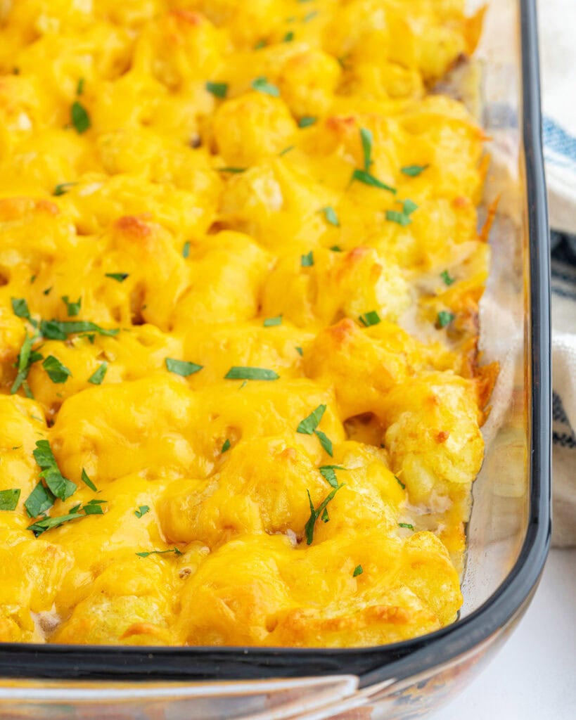 A baking pan of tater tot casserole topped with melted cheese and fresh parsley.