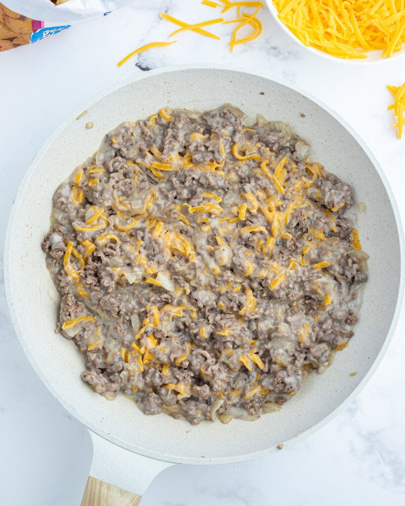 A saute pan of a creamy mixture coating ground beef.