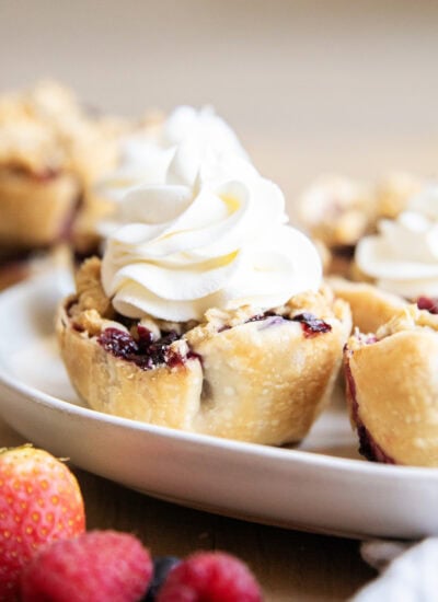 A Mini pie topped with whipped cream on a plate.