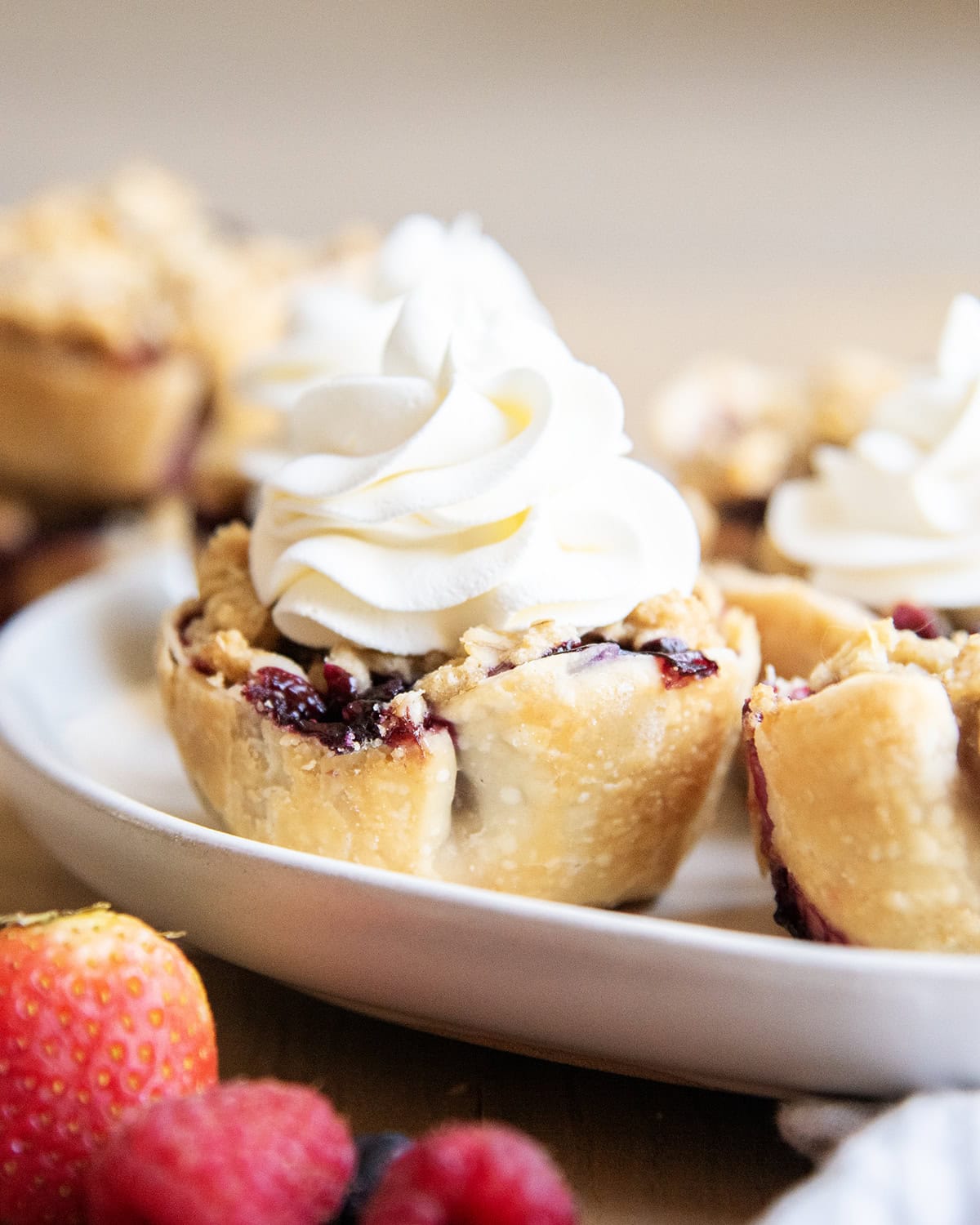 A Mini pie topped with whipped cream on a plate.