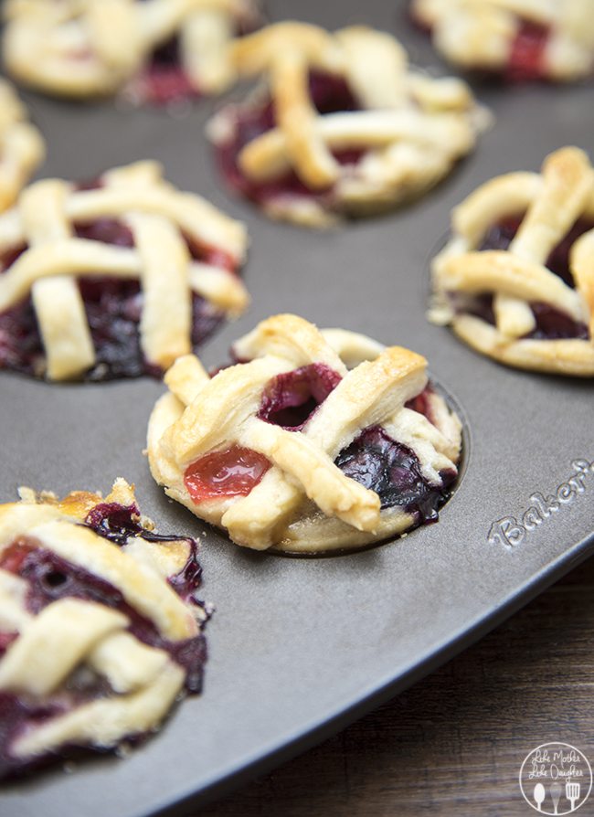 Mini berry pies in a mini muffin pan with a lattice crust.