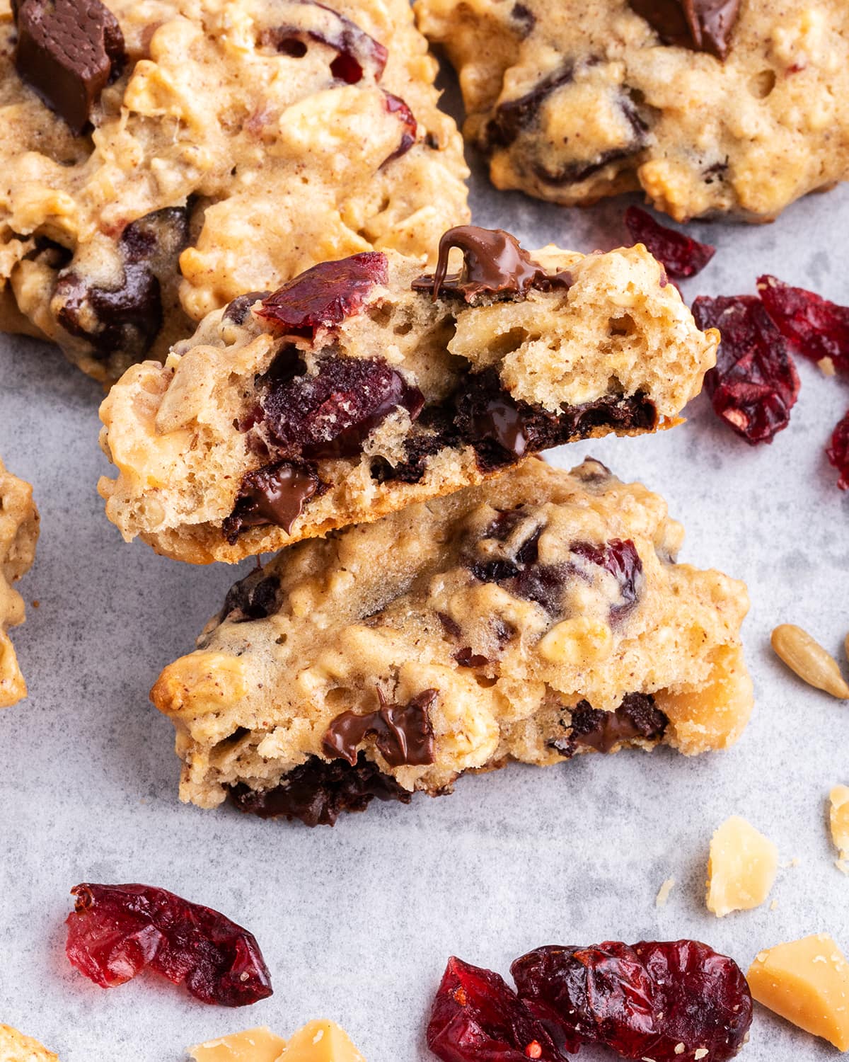 A hurricane cookie full of oats, nuts, chocolate and craisins split in half showing the middle of the cookie.