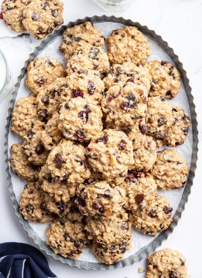 A pile of hurricane cookies loaded with chocolate and craisins, all set on an oval metal tray.