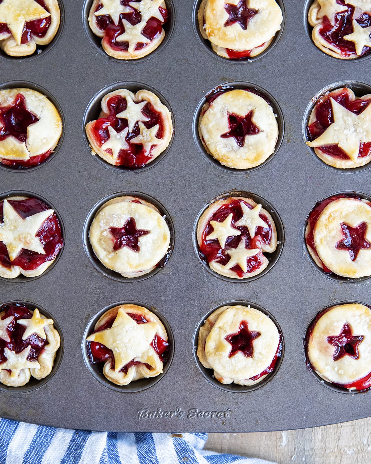 A mini muffin pan full of baked mini cherry pies. 