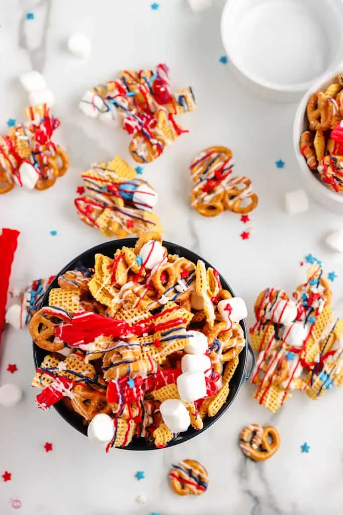 A bowl of patriotic chex mix drizzled with red and blue candy melts. 