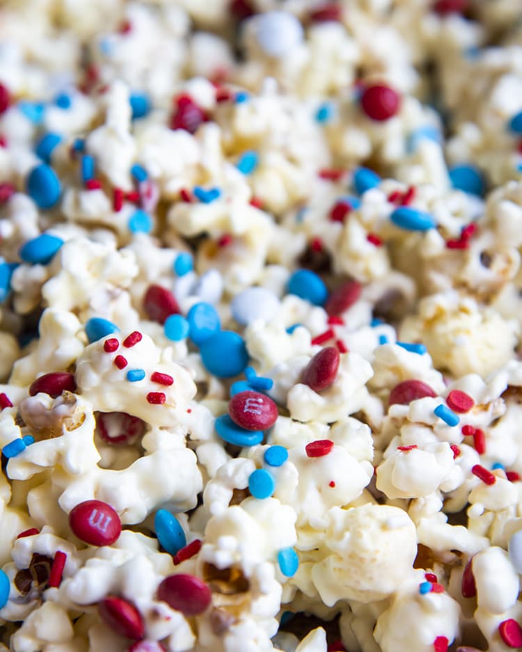 popcorn covered in white chocolate and red white and blue sprinkles and m&ms