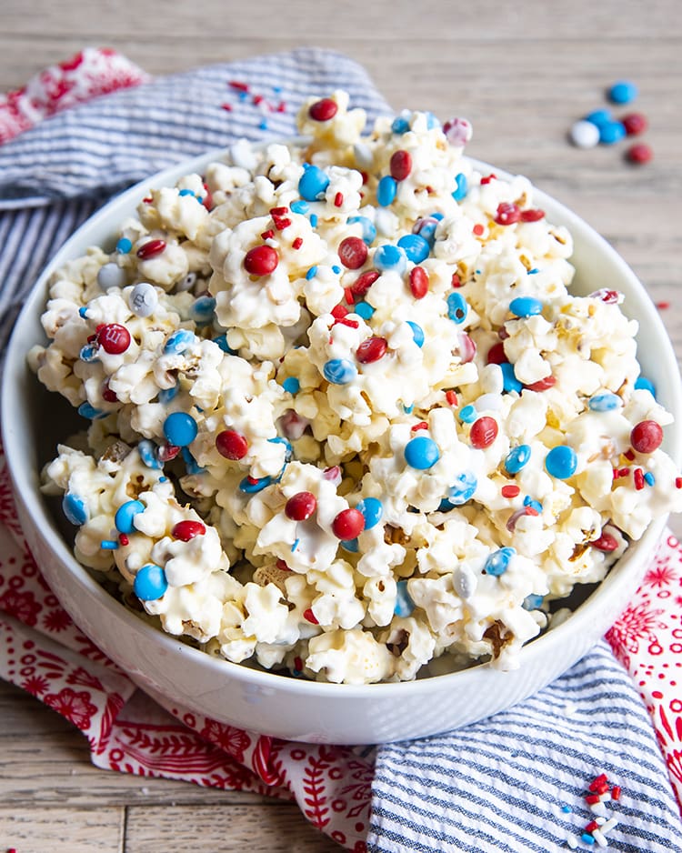 White Chocolate Popcorn with red white and blue m&ms and sprinkles in a white bowl