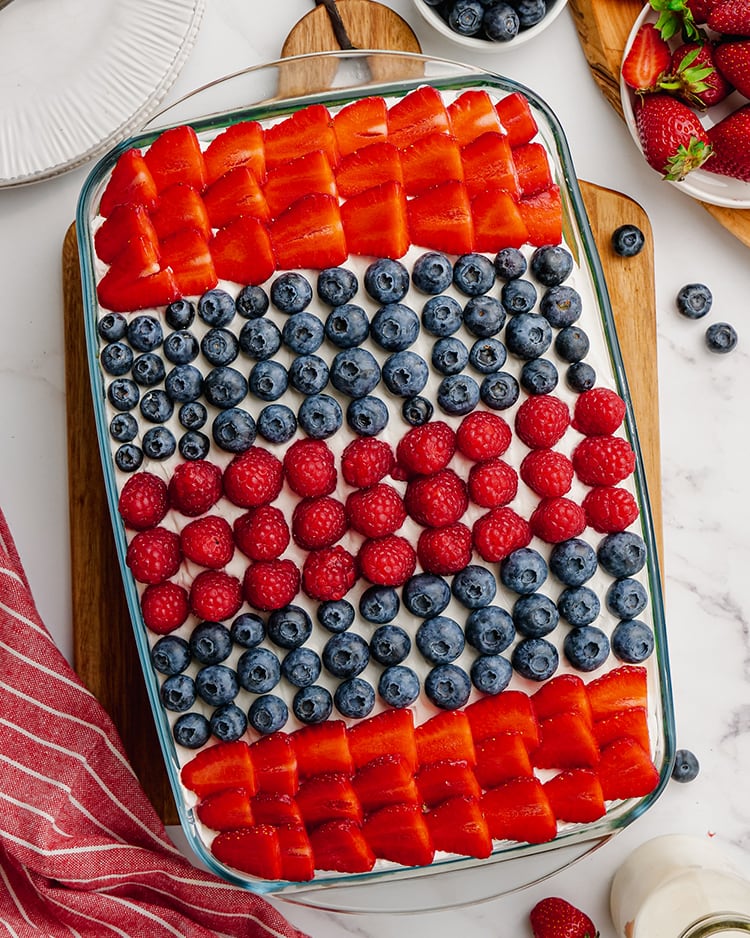 A cake in a pan with stripes of strawberries, blueberries and raspberries.