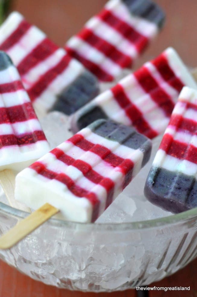 A  bowl of ice topped with striped red white and blue popsicles. 