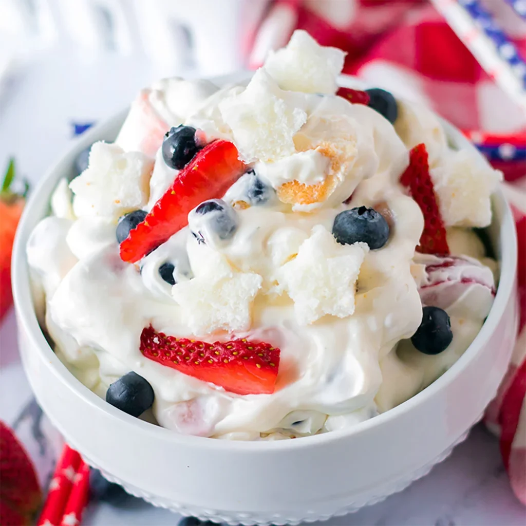 A bowl of cheesecake fluff salad, mixed with blueberries and strawberries. 