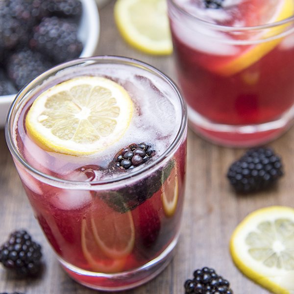 Angled view of blackberry lemonade in glasses.