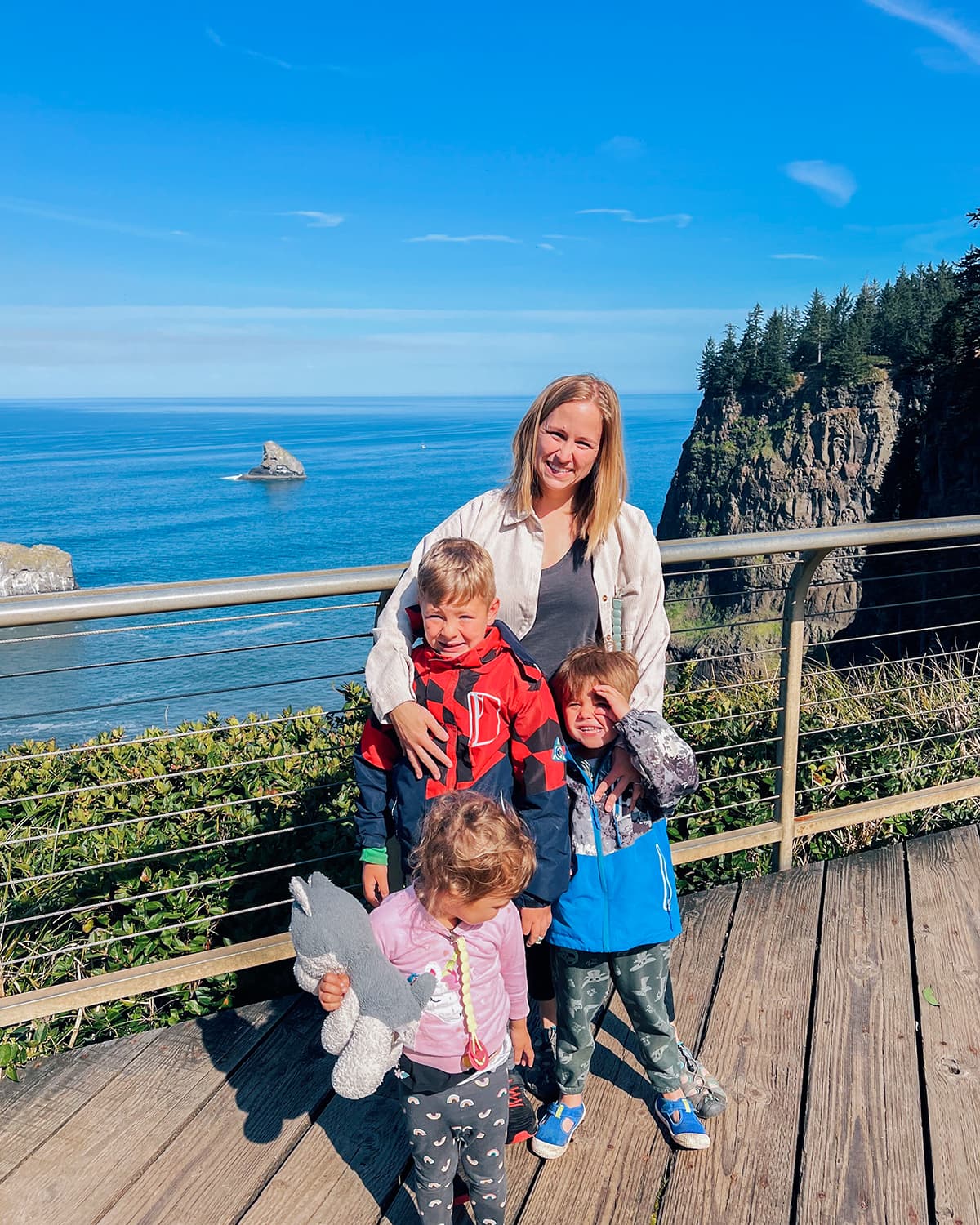 A woman with three children in front of an ocean view. 