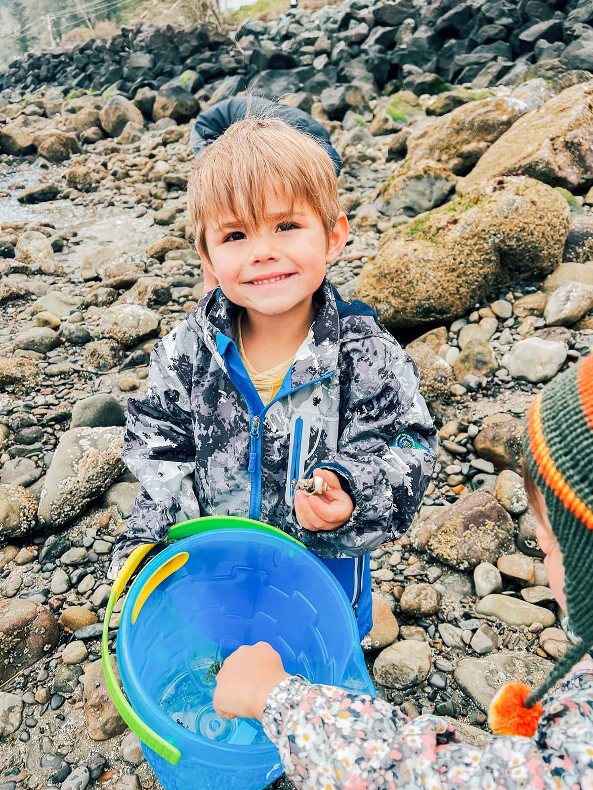 A boy holding a bucket with crabs in it. 