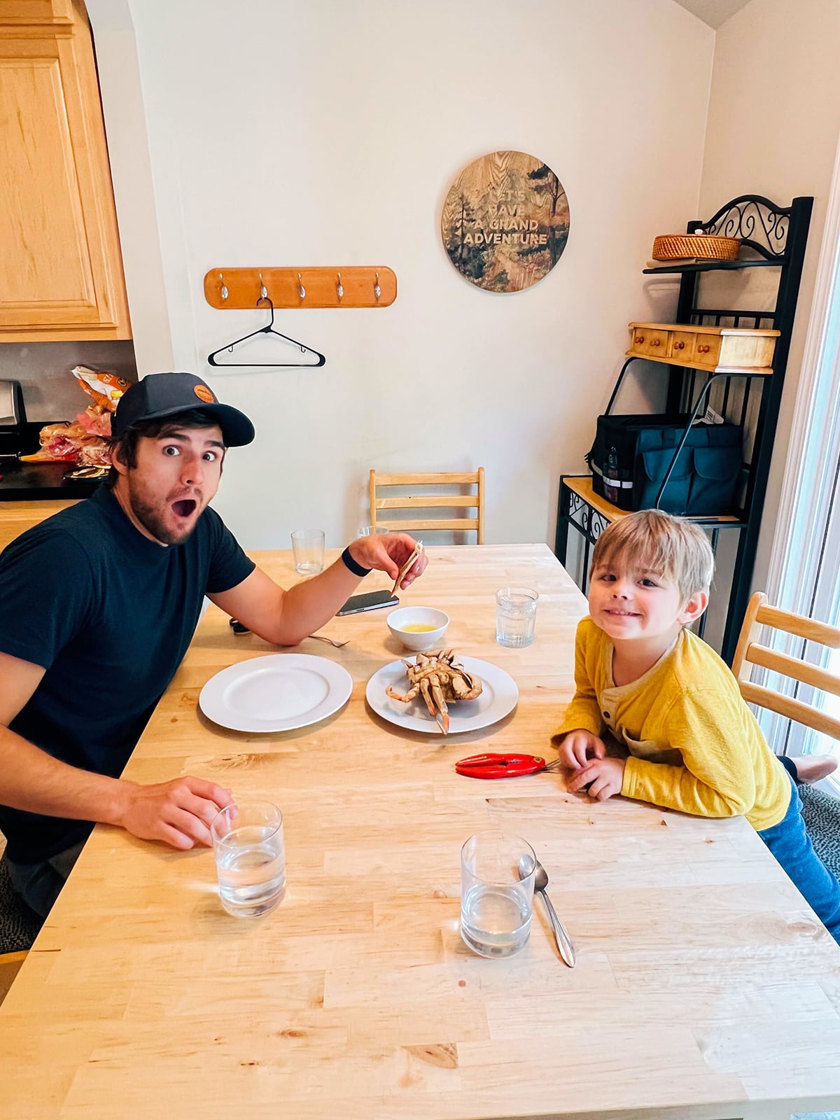 A man and a boy at a table with a crab in the middle. 