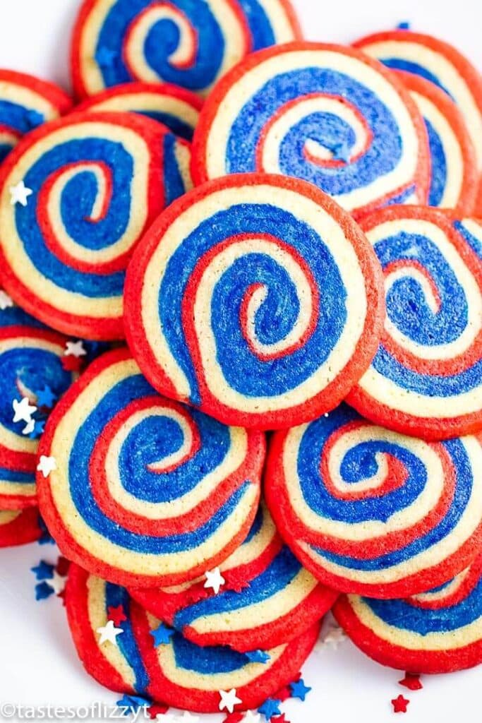 A pile of pinwheel cookies swirled with red, white and blue colors. 
