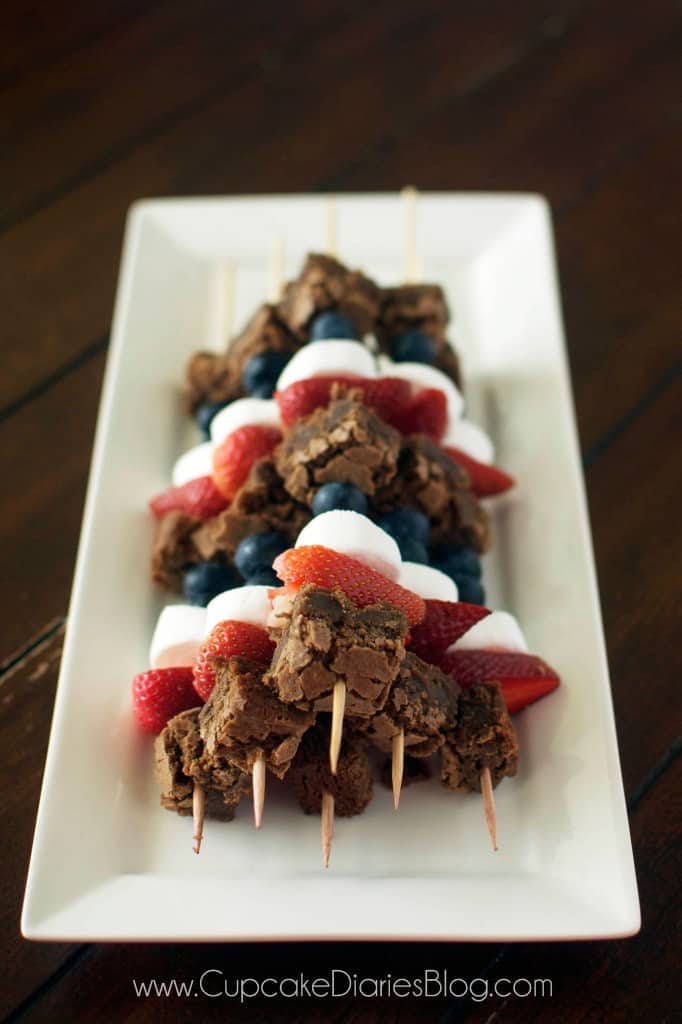A plate topped with red white and blue brownie skewers. 