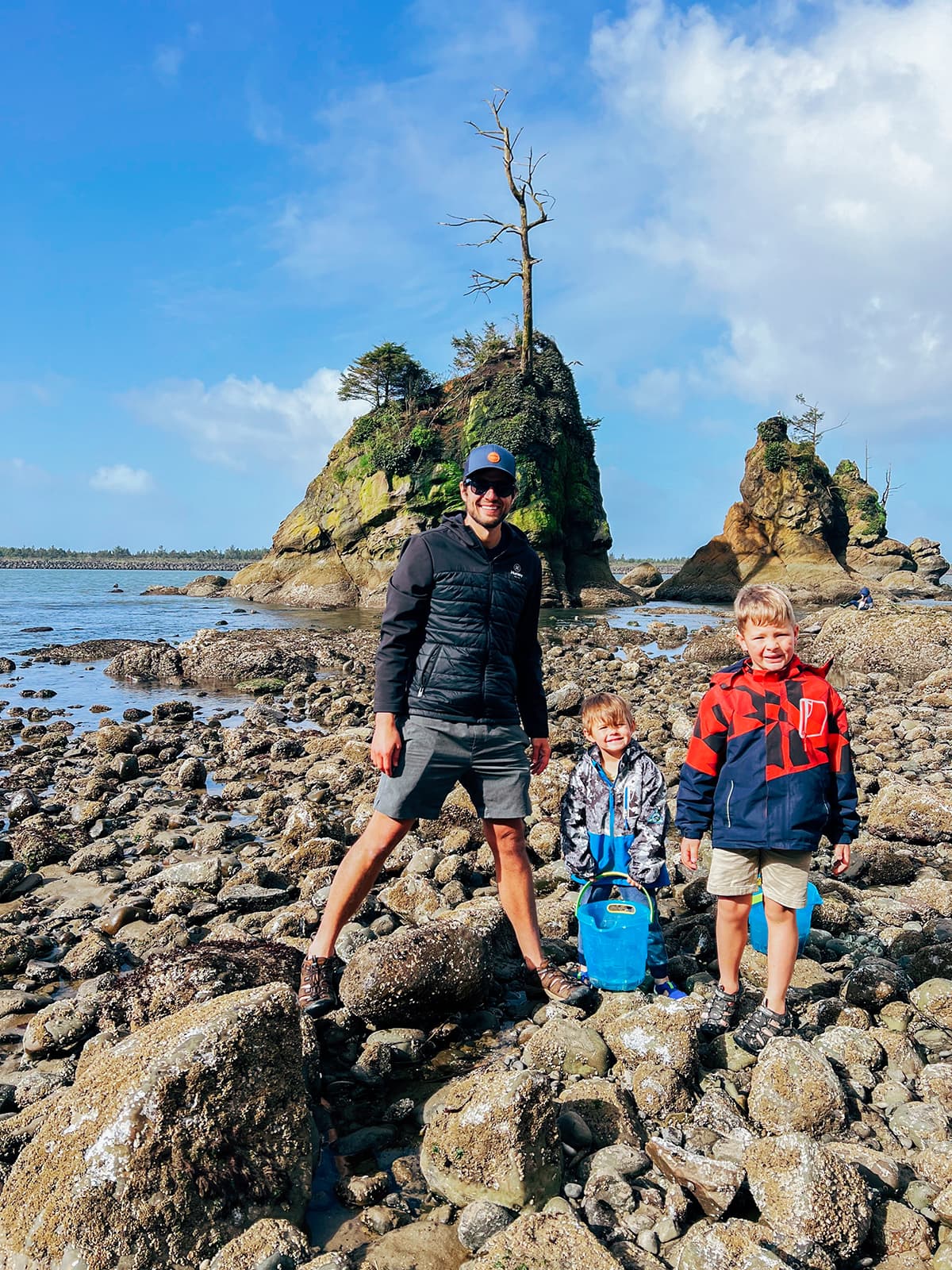 A man and two smaller boys in front of tide pools. 