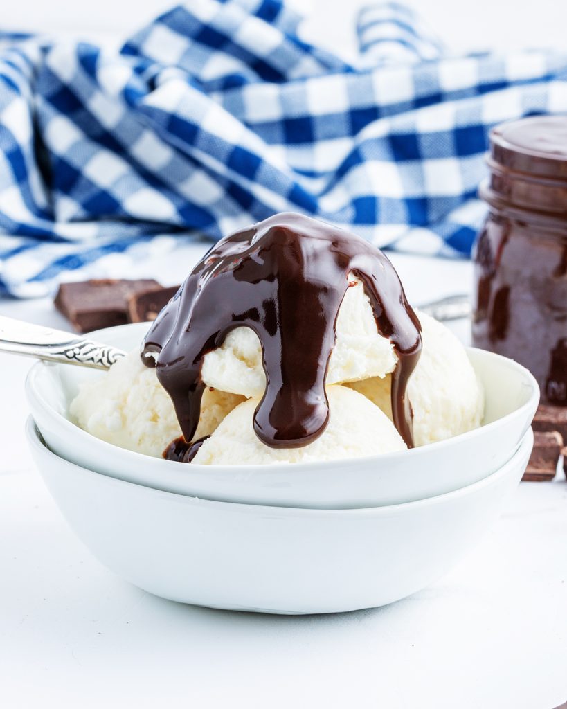 A bowl of vanilla ice cream topped with chocolate fudge sauce.