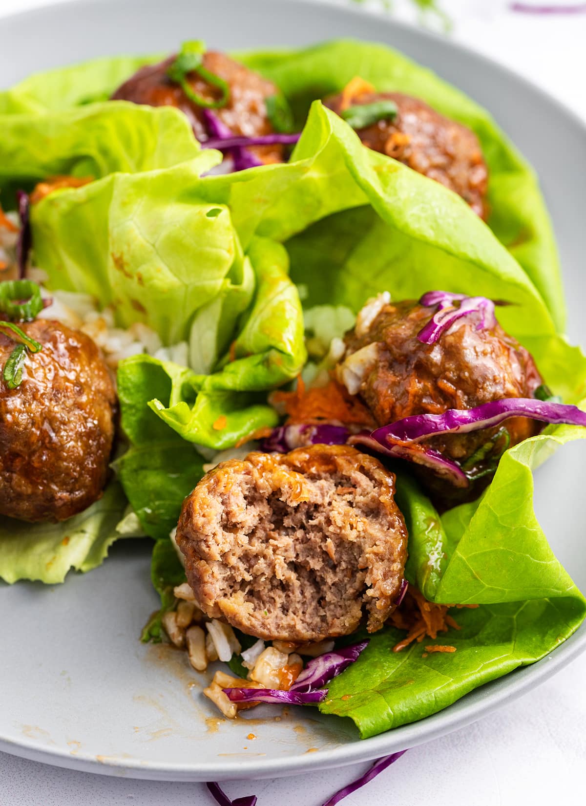 Teriyaki meatball lettuce wraps with a bite out of one of the meatballs.