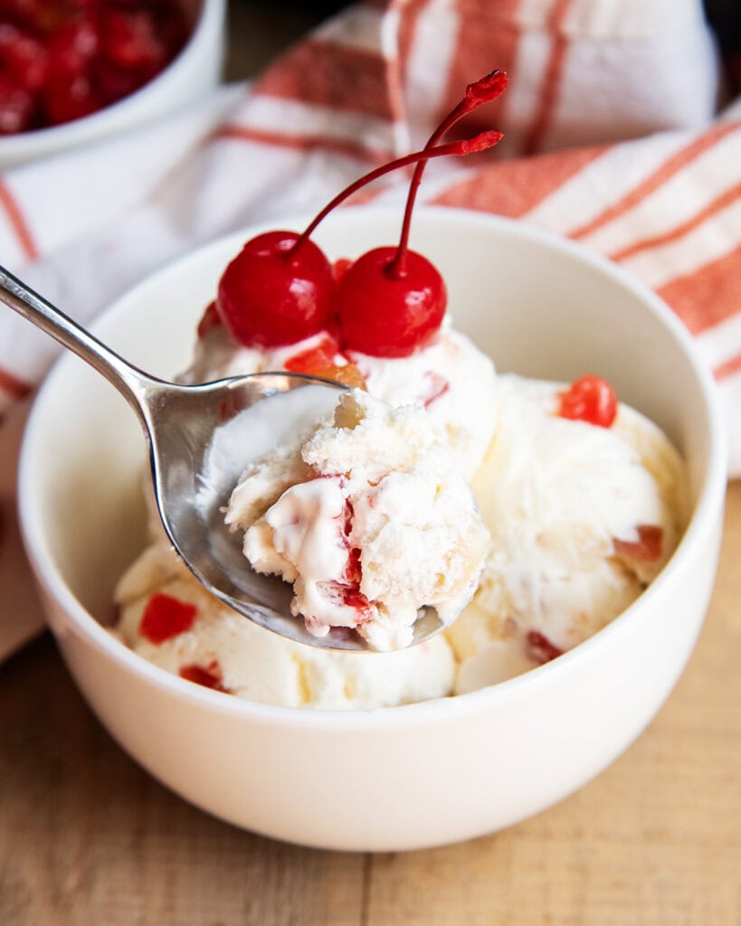 A spoonful of tutti frutti ice cream above a bowl of it.