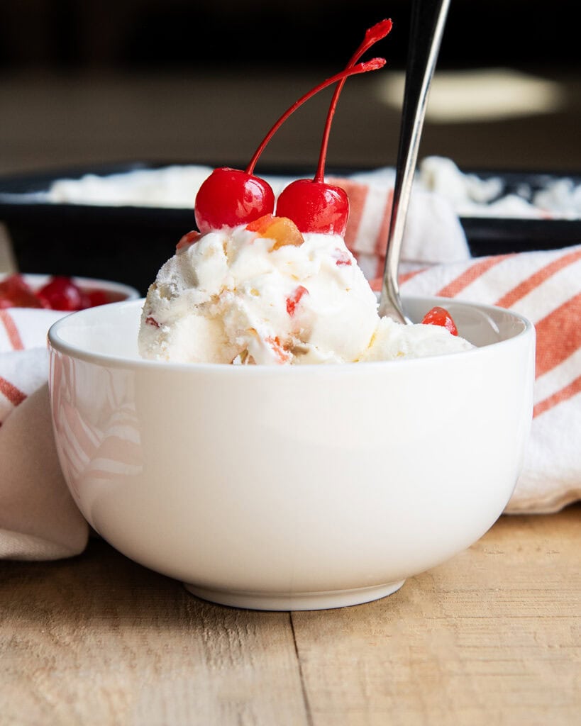 A bowl of ice cream topped with two maraschino cherries.