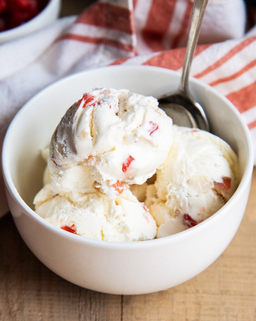 A bowl of scoops of tutti frutti ice cream full of candied fruit.