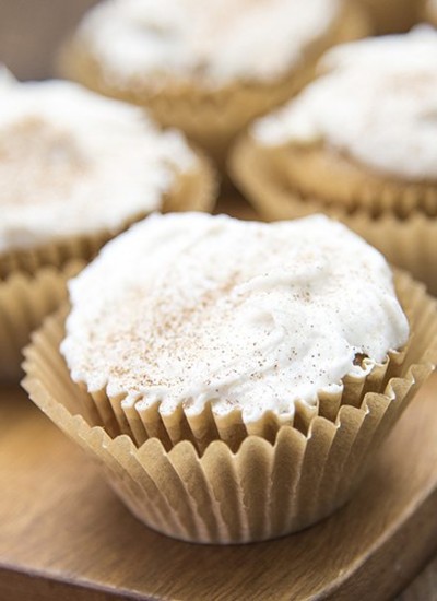 Angled view of apple beer cupcakes on a wood plank.