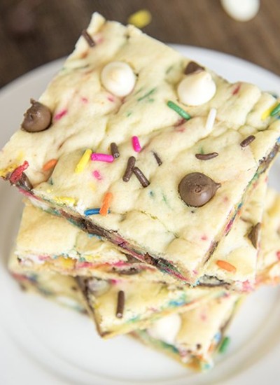 Above view of cake batter blondies stacked on a white plate.