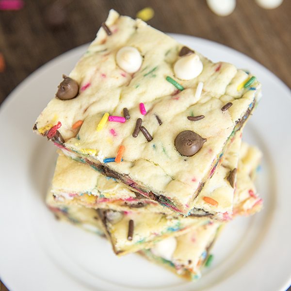 Above view of cake batter blondies stacked on a white plate.