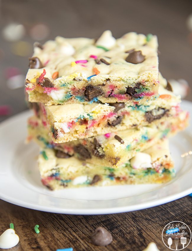 Cake batter blondies cut and stacked on a white plate showing multi-color sprinkles.