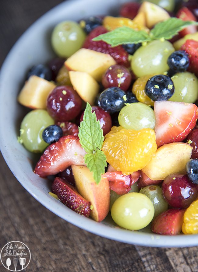Angled view of rainbow fruit salad in a white bowl.